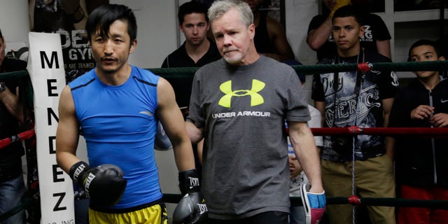 Zou Shiming, left, a two-time Olympic gold medalist and three-time World Amateur Champion from China, exits the ring with trainer Freddie Roach after a workout, Wednesday, June 8, 2016, at Mendez Gym in New York. Zou will be defending his WBO International flyweight title and No. 2 world rating in a 10-round bout against Jozsef Ajtai of Hungary,Saturday, June 11 at Madison Square Garden. (AP Photo/Mark Lennihan)