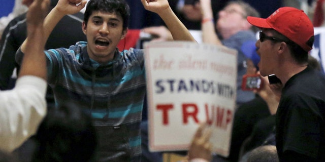 A protester (L) demonstrates during a U.S. Republican presidential candidate Donald Trump campaign rally in West Allis, Wisconsin, United States, April 3, 2016. REUTERS/Jim Young - RTSDEVW