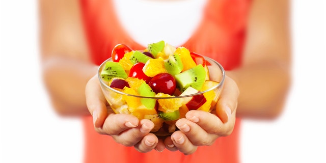Healthy mix fruit salad, closeup on fresh summer dessert, woman holds lunch bowl, selective focus on female hands, eating girl shallow dof, body weight care, health and diet concept