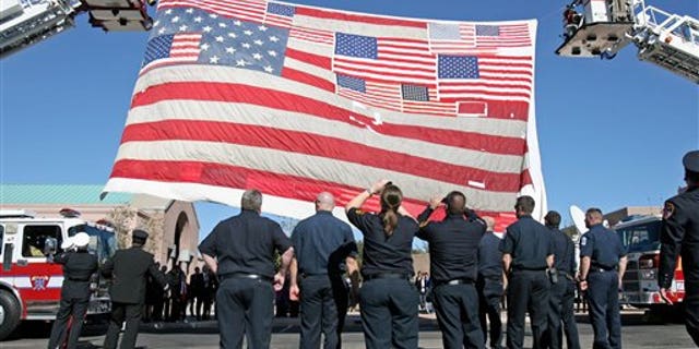 Jan. 13, 2011: Firefighters raise the large American flag recovered from Ground Zero after the 9/11 attacks outside the entrance at the St. Elizabeth Ann Seton Church for the funeral of 9-year-old Christina Taylor Green in Tucson, Ariz. Green, the youngest victim of Saturday's shooting in Tucson, was born on the day of the Sept. 11 attacks in 2001.