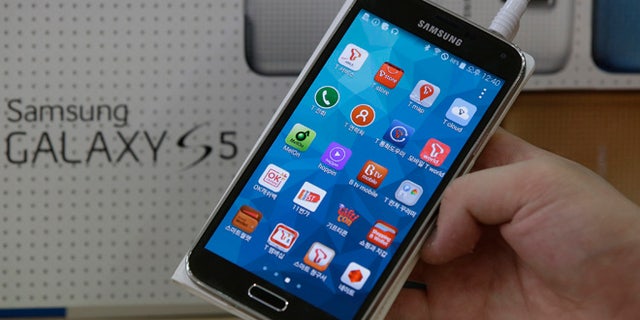 March 27, 2014: An employee shows Samsung's Galaxy S5 smartphone at a mobile phone shop in Seoul, South Korea.