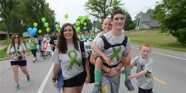 Braden Gandee rides aboard his brother Hunter's back who is walking along side sister, Kerragan and brother, Kellen as the Gandee family begins the 55 mile walk from Temperance, Mich., to Ann Arbor Friday, June 5, 2015. This walk is to raise awareness about cerebral palsy. (Tom Hawley/The Monroe Evening News via AP)