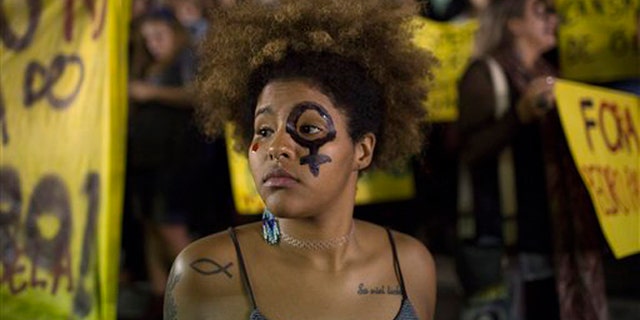 A woman wearing a female gender symbol attends a protest against the gang rape of a 16-year-old girl in Rio de Janeiro, Brazil, Friday, May 27, 2016. The assault last Saturday came to light after several men joked about the attack online, posting graphic photos and videos of the unconscious, naked teen on Twitter. (AP Photo/Leo Correa)