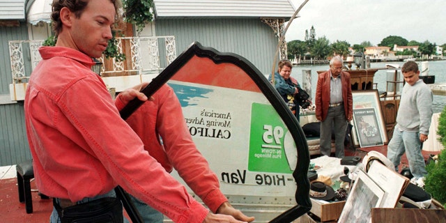 Mike Levin examines a mirror December 29 that once hung in the bedroom of the houseboat where Gianni Versace's killer, Andrew Cunanan was found dead. The owner of the famed houseboat where the serial killer committed suicide held a yard sale of household goods from the houseboat, which partially sunk seven days ago along Miami Beach's intercoastal waterways, December 29.VERSACE HOUSEBOAT
