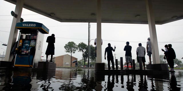 People watch heavy rain from the relative safety of a flooded gas station caused by Tropical Storm Harvey on Sunday, Aug. 27, 2017, in Houston.