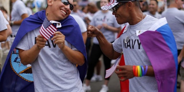 Matthew Avila (L), active duty gunners mate 2nd class U.S. Navy, receives a punch in the arm from former EN2 U.S. Navy's Ray Cordero as they prepare to march with active and non-active U.S. military personnel who are participating for the first time in San Diego's Gay Pride Parade in San Diego, July 16, 2011.