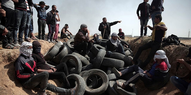 April 6, 2018: Palestinian protesters sit over tens of tires collected to be burned during a protest at the Gaza Strip's border with Israel.