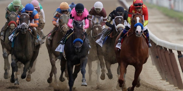 Justify, right, ridden Mike Smith leads the field at the end of the backstretch during the Belmont Stakes horse race.