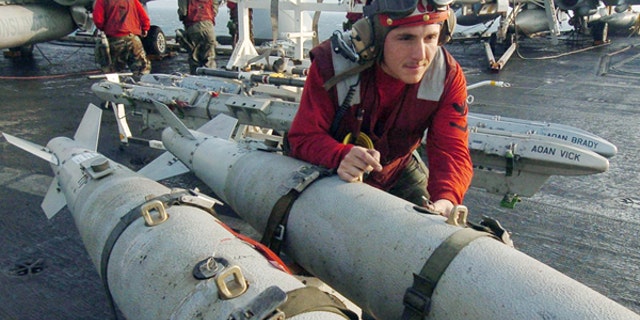 U.S. Aviation Ordnanceman 3rd Class Joshua Silva, assigned to "Gunslingers" of Strike Fighter Squadron One Zero Five (VFA-105), helps push a weapons skid loaded with three GBU-38 500 pound satellite guided bombs on the flight deck aboard USS Harry S. Truman .