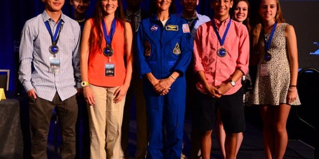 Anna-Sophia Boguraev, 16, of Bedford, New York, won the first ever Genes in Space contest for student experiments on the International Space Station. She can be seen here standing to the left of NASA astronaut Sunita Williams (center). They are