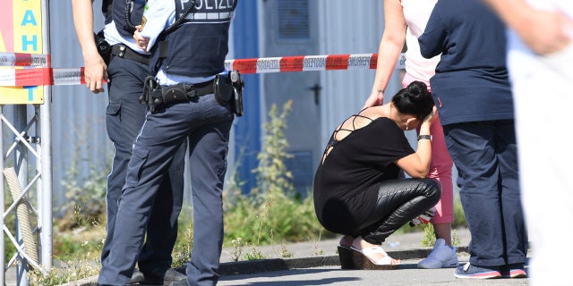 A visitor, center, waits to be questioned by police near a discotheque in Constance, at Lake Constance, Germany, Sunday, July 30, 2017.