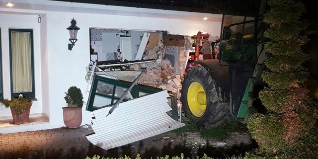 A tractor stands in front of a damaged house after it broke through the wall in Buende, north-western Germany, Thursday, Jan. 26, 2017. Unknown intruders steered the tractor into the house and broke through the wall in order to steal a safe. The residents were not injured. (Nord-West-Media TV/dpa via AP)