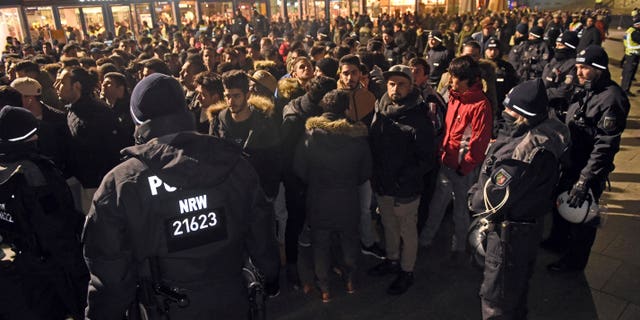 Police officers surround a group of men in front of the Cologne, western Germany, main station, Saturday, Dec. 31, 2016, where a string of robberies and sexual assaults last year that were blamed largely on migrants from North Africa prompted nationwide outrage. (Henning Kaiser/dpa via AP)