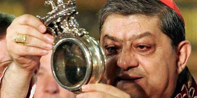 File photo - The archbishop of Naples holds a flask believed to contain drops of liquefied blood of San Gennaro in 2006. (AP Photo/Salvatore Laporta, File)