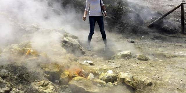 A woman takes a close look at a steaming fumarola at the Solfatara crater bed in Italy's Campi Flegrei last April. (AP Photo/Frances D'Emilio)