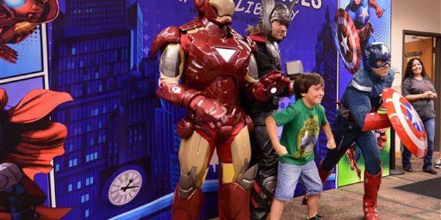 A boy strikes a pose with three superheroes in this file photo.