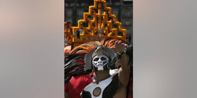 A man with his face painted and dressed as an Aztec Indian gestures during the celebration of the Day of the Dead, in Mexico City, Wednesday, Nov. 2, 2016.