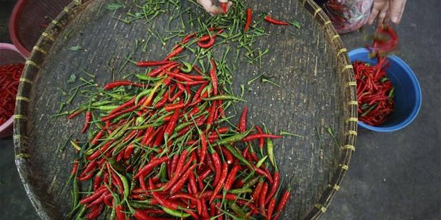 A local vendor sorts through Thai chili peppers in Bangkok.