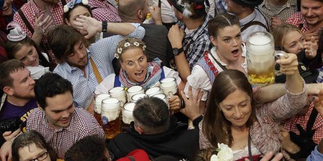 FILE - In this Saturday, Sept. 17, 2016 file photo a waitress is surrounded by visitors during the opening ceremony of the 183rd Oktoberfest beer festival in Munich, southern Germany.
