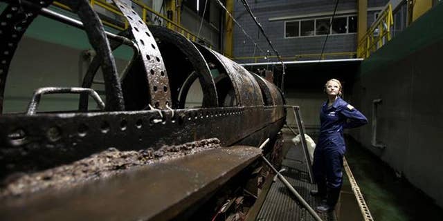 Conservator Anna Funke stands next to the HL Hunley at the Warren Lasch Conservation Center on Wednesday. (Michael Pronzato/The Post And Courier via AP)