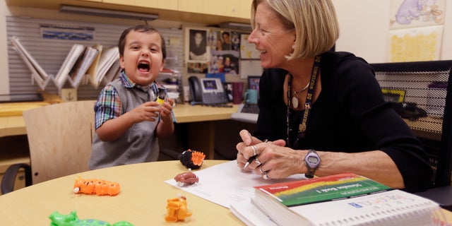 In a photo from Thursday, Oct. 22, 2015, in Ann Arbor, Mich., Grant Hasse yells out a word next to Lynn Driver, a speech-language pathologist at the University of Michigan's C.S. Mott Children's Hospital. (AP Photo/Carlos Osorio)