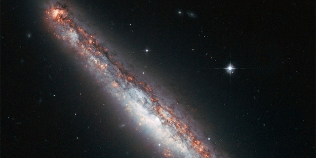 This NASA/ESA Hubble Space Telescope image shows the edge-on profile of the slender spiral galaxy NGC 5775, which is surrounded by a halo of gas that astronomers suspect is kicked up by star explosions like a galaxy-size fountain.