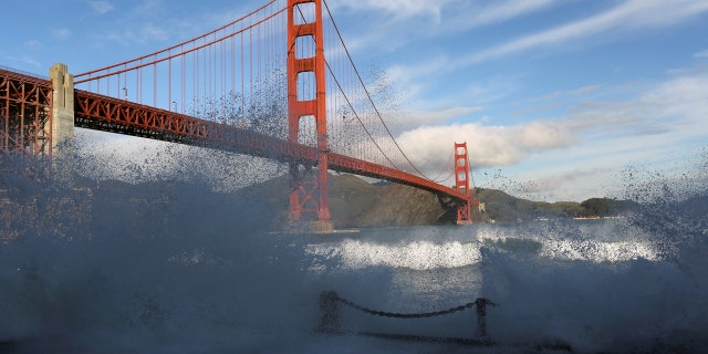 Waves crash against a sea wall in San Francisco Bay beneath the Golden Gate Bridge in San Francisco, California December 16, 2014.