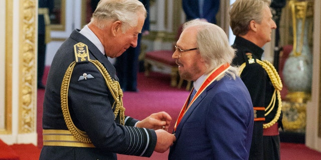 Singer and songwriter Barry Gibb talks with Prince Charles, left, during an Investiture ceremony to award a knighthood to Gibb, at Buckingham Palace in London, Tuesday June 26, 2018.