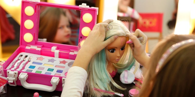 A young girl paints the face of a doll by the company Simba during the press preview of the 66th International Toy Fair in Nuremberg January 27, 2015. (REUTERS/Michaela Rehle)