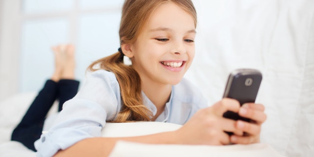 education, school, technology and internet concept - little student girl with smartphone at home