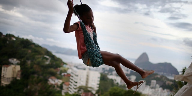RIO DE JANEIRO, BRAZIL - MARCH 22:  A child swings on a swing in the Prazeres pacified 'favela' community on March 22, 2014 in Rio de Janeiro, Brazil. The 'favela' was previously controlled by drug traffickers and is now occupied by the city's Police Pacification Unit (UPP). A number of UPP's were attacked by drug gang members on March 20 and some pacified favelas will soon receive federal forces as reinforcements. The UPP are patrolling some of Rio's favelas amid the city's efforts to improve security ahead of the 2014 FIFA World Cup and 2016 Olympic Games.  (Photo by Mario Tama/Getty Images)