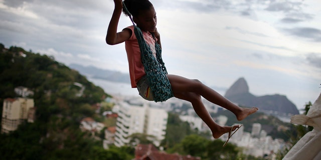 RIO DE JANEIRO, BRAZIL - MARCH 22: A child swings on a swing in the Prazeres pacified 'favela' community on March 22, 2014 in Rio de Janeiro, Brazil. The 'favela' was previously controlled by drug traffickers and is now occupied by the city's Police Pacification Unit (UPP). A number of UPP's were attacked by drug gang members on March 20 and some pacified favelas will soon receive federal forces as reinforcements. The UPP are patrolling some of Rio's favelas amid the city's efforts to improve security ahead of the 2014 FIFA World Cup and 2016 Olympic Games. (Photo by Mario Tama/Getty Images)