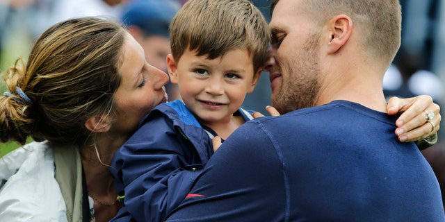 New England Patriots quarterback Tom Brady and his wife Gisele Bundchen embrace their son Benjamin Brady after a joint workout with the Tampa Bay Buccaneers at NFL football training camp, in Foxborough, Mass., Tuesday, Aug. 13, 2013. (AP Photo/Charles Krupa)