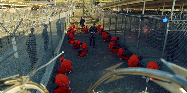 Jan 11, 2002: Detainees in orange jumpsuits sit in a holding area under the watchful eyes of military police during in-processing to the temporary detention facility at Camp X-Ray of Naval Base Guantanamo Bay. (Reuters)
