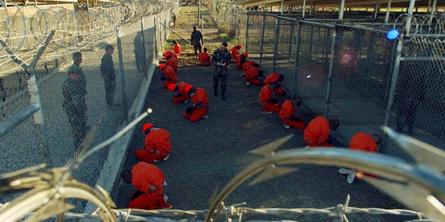 Jan 11, 2002: Detainees in orange jumpsuits sit in a holding area under the watchful eyes of military police during in-processing to the temporary detention facility at Camp X-Ray of Naval Base Guantanamo Bay. (Reuters)