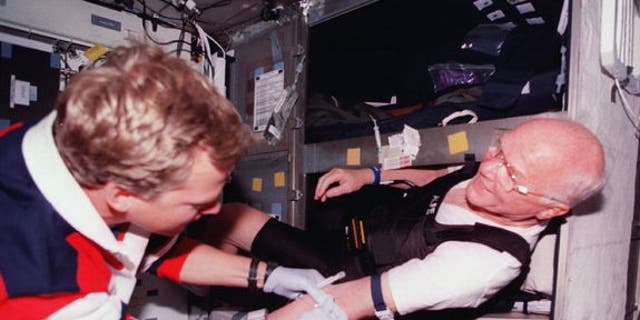 Astronaut John Glenn (right) gets bloodwork done in his bunk aboard space shuttle Discovery in 1998. About half of astronauts require sleep medication at some point during their flights, NASA said.