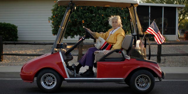 A woman rides in a golf cart with her dog in Sun City, Arizona, January 6, 2013.