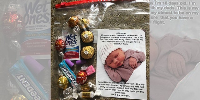 Two dads flying home with their new baby handed out goody bags and apology notes to the other passengers.