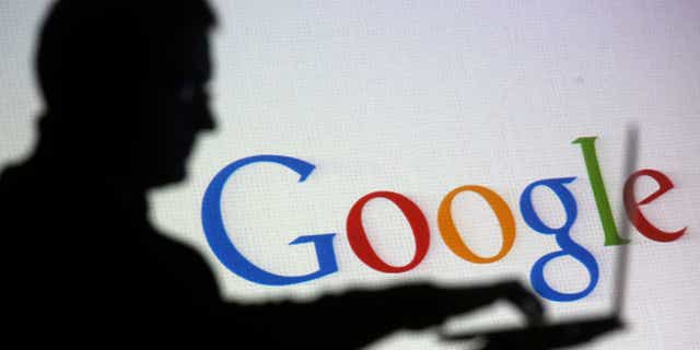 Oct. 29, 2014: People are silhouetted as they pose with laptops in front of a screen projected with a Google logo, in this picture illustration taken in Zenica.