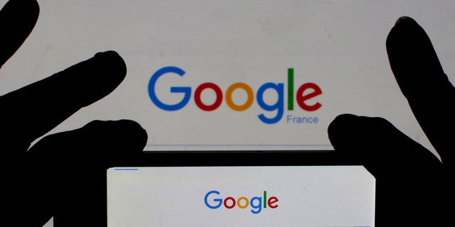 A woman holds her smart phone which displays the Google home page, in this picture illustration taken Feb. 24, 2016. (REUTERS/Eric Gaillard/Illustration)