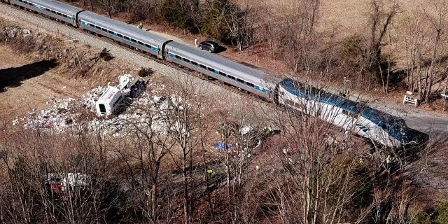 The wreckage of a garbage truck lies beside an Amtrak passenger train
