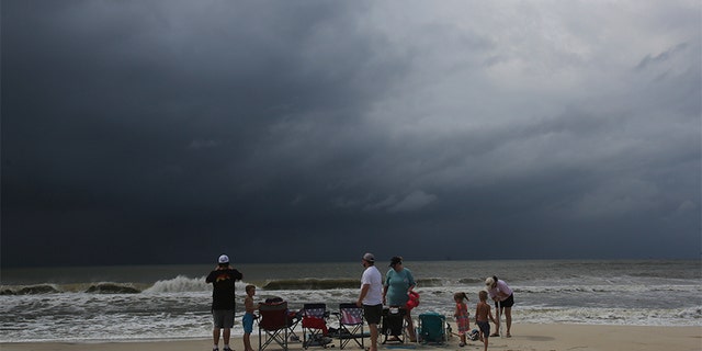 A family watches the first rains clouds from Tropical Storm Gordon roll in on Tuesday in Dauphin Island, Ala.