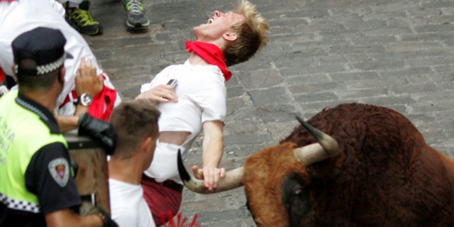 July 12, 2013: A runner is gored by an "El Pilar" fighting bull during the running of the bulls at the San Fermin festival, in Pamplona, Spain.