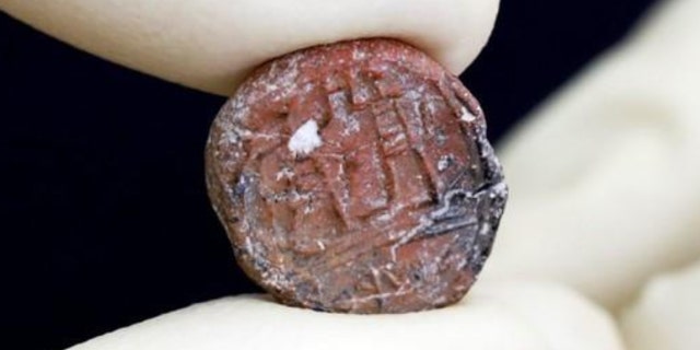 A conservator shows a 2,700-year-old clay seal impression which archaeologists from the Israel Antiquities Authority say belonged to a biblical governor of Jerusalem and was unearthed in excavations in the Western Wall plaza in Jerusalem's Old City January 1, 2018.