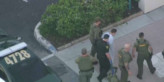 The suspect was escorted by police in his hospital gown.