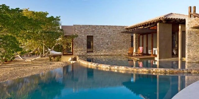 The villa, made with wood and rock, is connected by pathways through water features that give the illusion that the villa is suspended over the Pacific.