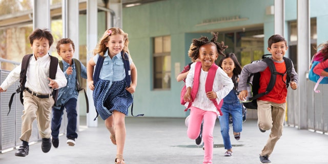 Group of elementary school kids running in a school corridor