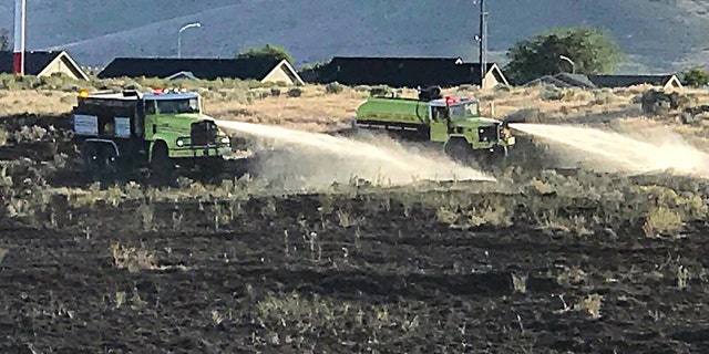 Firetrucks spray scorched earth after a man set an American flag blanket on fire that spread into a wildfire on Memorial Day weekend in Washington state, authorities said.
