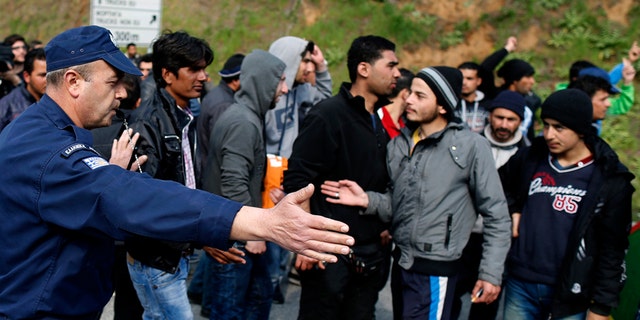 March 28, 2016: A police officer blocks migrants near the Evzoni border crossing, Greece.