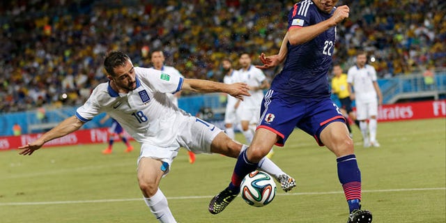 June 19, 2014: Greece's Giannis Fetfatzidis, left, challenges Japan's Maya Yoshida during the group C World Cup soccer match between Japan and Greece at the Arena das Dunas in Natal, Brazil.